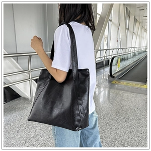 Detailed view of black faux leather tote bag showing large capacity and soft texture on model