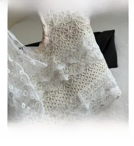 Gros plan d'un sac à main en dentelle crochetée crème avec des motifs évidés élégants