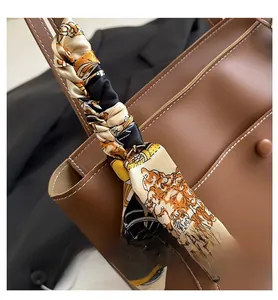 Close-up of silk scarf with vintage tiger print wrapped on brown leather tote handle