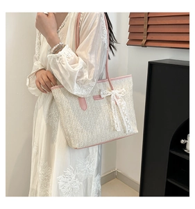 Détail du sac cabas en paille avec anses en cuir rose et noeud en dentelle délicat