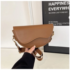 Detail shot of brown saddle bag featuring striped wide strap and gold hardware