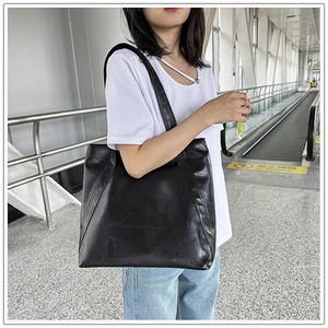 Close-up of a large black tote bag featuring unique geometric patchwork on soft leather