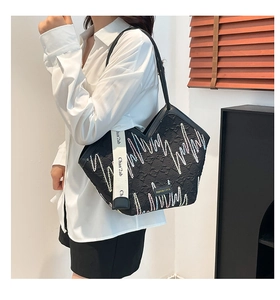 Detail of black quilted tote bag with wave embroidery and branded canvas shoulder strap