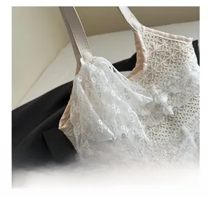 Détail d'un sac cabas en dentelle blanche avec motifs floraux et grand nœud en maille