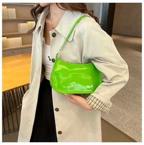 Dettaglio della borsa baguette verde neon lucida con finiture dorate e tracolla
