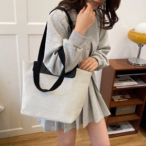 Minimalist canvas tote bag with black shoulder straps and spacious trapezoidal design