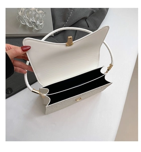 Close-up of open white and silver handbag showing dual compartments and gold handle