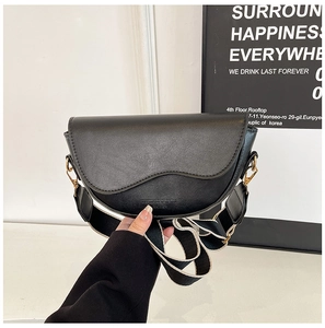 Detail of black matte saddle bag featuring striped wide strap and gold hardware