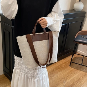 Minimalist off-white canvas tote bag with brown leather straps for daily commute