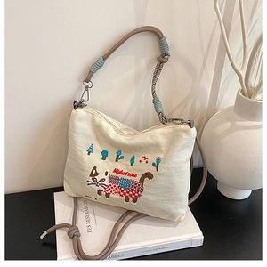 Close-up of canvas tote bag with cat embroidery and decorative rope handle detail