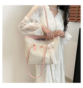 Détail du sac cabas en paille avec nœud en dentelle blanche et anses en cuir rose