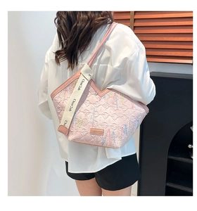 Detail of pink quilted tote bag showing colorful embroidery and stylish wide woven strap