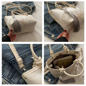 Macro shot of cream bucket bag showing floral patterns, tassels, and spacious interior