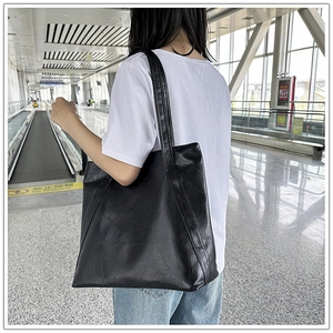 Detail of the black leather tote bag showing large capacity and natural texture on the strap