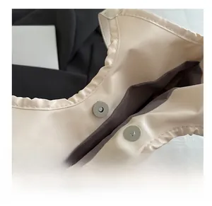 Gros plan du fermoir magnétique argenté sur sac en cuir beige avec coutures précises