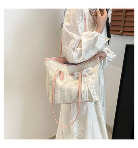 Détail du sac cabas en paille beige avec anses roses et nœud en dentelle blanche délicat