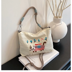 Detail of cute cat embroidery and textured rope strap on large canvas shoulder bag