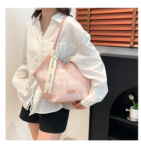 Pink tote bag detail with quilted texture and decorative wide fabric shoulder strap