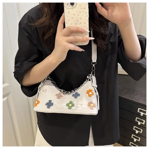 Detail of white crocodile pattern baguette bag with colorful plush flower patches