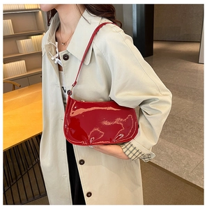 Modella indossa borsa baguette in pelle verniciata rossa con cappotto beige
