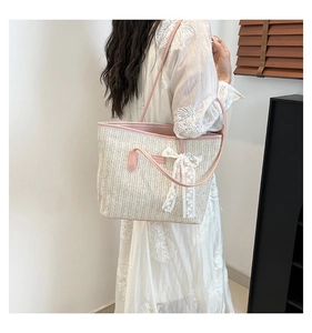 Détail du sac cabas en paille d'été avec bordure en cuir rose et nœud en dentelle