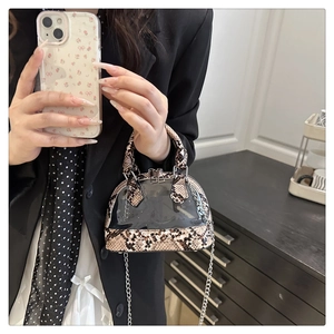 Detail einer transparenten Muscheltasche mit dunklem Schlangenmuster und Metallkette