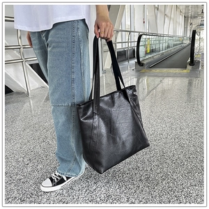 Detailed view of large black tote bag with pleated texture and double top handles