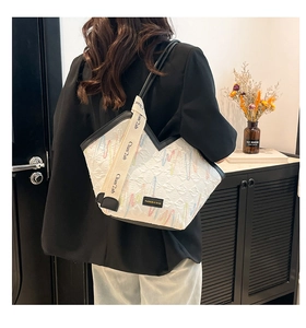 Close-up of textured white tote bag with colorful wave embroidery and black trim detail