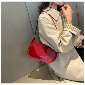 Vista laterale di una borsa a spalla in vernice rossa abbinata a un cappotto invernale beige
