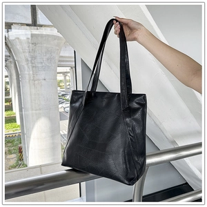 Close-up of black PU leather tote bag with natural grain texture and long handles