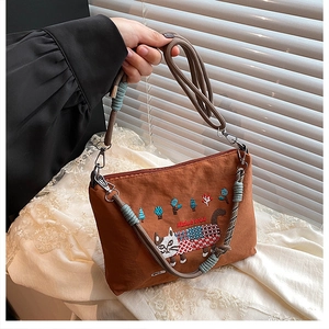 Close-up of brown embroidered cat crossbody bag featuring a woven rope handle