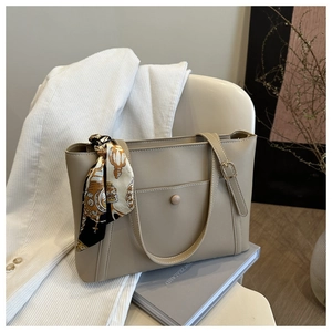 Detail of beige PU leather tote bag with silk scarf and magnetic pocket on a chair