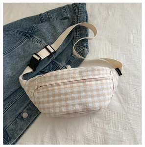 Detailopname van de corduroy geruite heuptas met verstelbare riem op denim ondergrond
