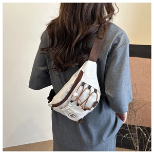 Dettaglio della borsa da petto in nylon bianco con cinghie marroni sul modello