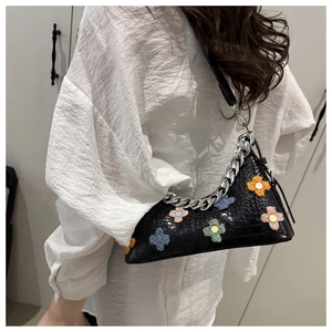 Detail of crocodile pattern baguette bag with colorful crochet floral patches and chain