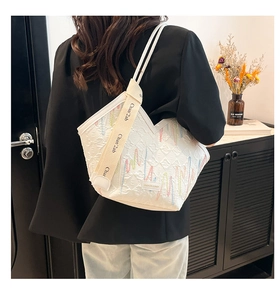 Detail shot of the white quilted tote bag featuring colorful wavy embroidery and wide strap