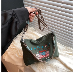 Detail of green canvas bag featuring a cute cat embroidery and decorative cord straps