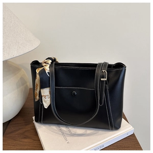 Detail of black PU tote bag featuring white contrast stitching and a printed silk scarf handle