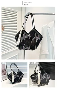 Detail of black quilted tote bag with zigzag embroidery and branded ribbon attachment
