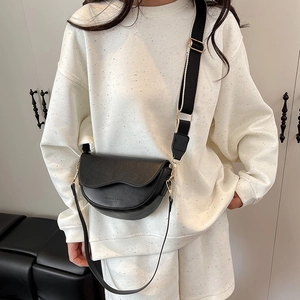 Black leather saddle crossbody bag with wavy flap design and wide fabric strap for women