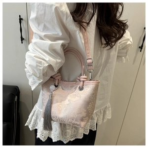 Detail of pink embroidered bucket bag with traditional scenery and grey tassel charm
