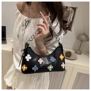 Detail of black crocodile texture bag with colorful plush flower charms and silver chain