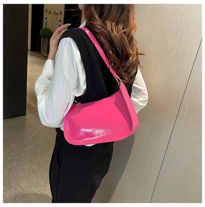 Dettaglio di una borsa a tracolla hobo in pelle verniciata rosa acceso con zip dorate