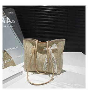 Détail du sac en paille avec nœud en dentelle blanche et anses en cuir marron