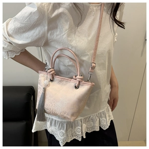 Detail of pink satin mini tote with floral patterns and a decorative grey tassel charm