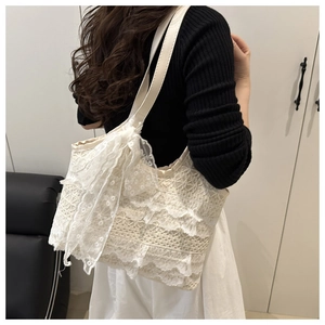Gros plan d'un sac cabas en dentelle blanche avec motifs floraux et grand nœud décoratif