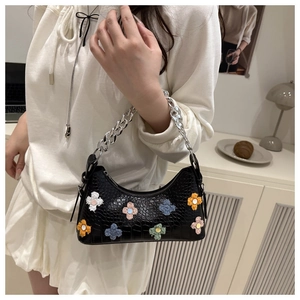 Detail of black croc-effect baguette bag with colorful floral motifs and silver chain
