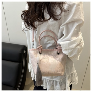 Close-up of pink jacquard floral handbag with elegant grey tassel and bead charm
