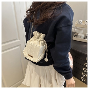 Detail of a mini bucket bag with faux snake skin texture and elegant pearl handle