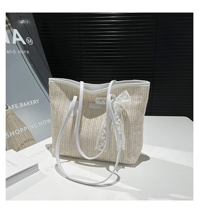 Détail du sac cabas en paille avec bandoulières en cuir blanc et nœud en dentelle chic